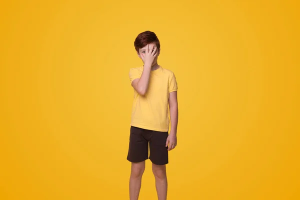 stock image Young caucasian boy put hand on face, facepalm epic fail isolated on yellow background studio portrait. People lifestyle concept