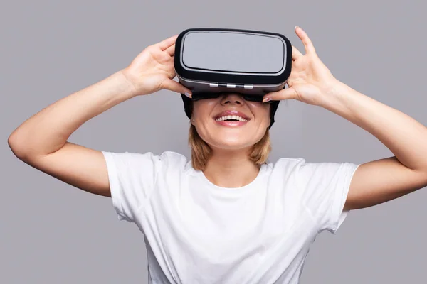 Portrait of young woman gamer playing VR games on gray background, VR gaming. 3d portrait. Futuristic lifestyle. Play online. Digital technology entertainment.