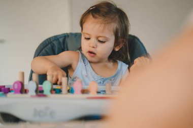Happy small curious caucasian baby girl at home engaged in funny activity with her mother. Childcare concept. Education concept. Family activity concept. Happy