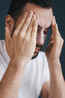 Evdeki kanepede otururken sinagoglarına dokunan ve gözlerini kapalı tutan sinirli genç adamın yakın plan portresi. Bitkin, hasta, yorgun.