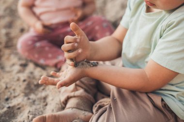 Bahçedeki kumu keşfeden bir çocuğun görüntüsü. Küçük bahçe. Yaz tatili. Sağlıklı bir yaşam tarzı tatili. Bahçe doğası.