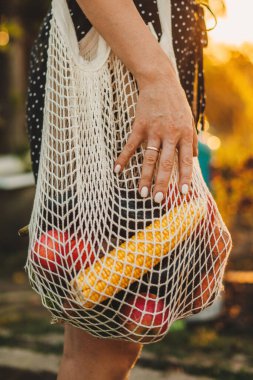 Kadın omuz omuza, ev bahçesinde içi taze sebzelerle dolu bir çanta, kırpılmış bir manzara. Sürdürülebilirlik ve organik ev yapımı gıda kavramı