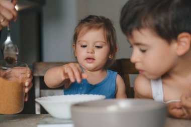 Anne ve çocuklar mutfakta birlikte yemek pişirirken krep hamuru veya kek karışımı hazırlıyorlar. Aile yemeği tatlı, çocuk öğrenme ve abur cubur pişirme