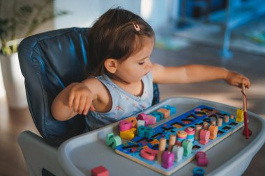 Sevimli bebek evde renkli oyuncaklarla eğleniyor. Bebek gelişimi, çalmayı öğrenmek. Çocuk sorunları çözmeyi ve bilişsel gelişimi öğreniyor