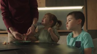 Güzel iki çocuk birlikte otururken dizüstü bilgisayardan izliyorlar. Evde kahvaltıda modern aletler kullanmak. Çocuk ve teknoloji kavramı