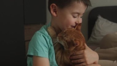 Küçük çocuk, kedi yavrusuyla yatakta oturup, yüzünü yalarken eğleniyor. Evcil kedi. Arkadaşlık kavramı. Mutlu aile çocuğu konsepti.