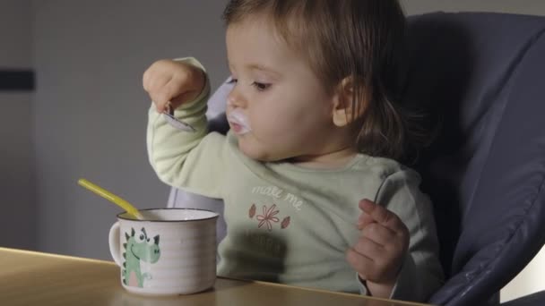 Dziewczynka Pijąca Mleko Łyżeczką Kubka Siedząca Wysokim Krześle Kuchni Osoba — Wideo stockowe