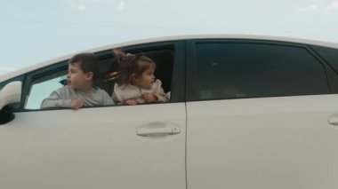 Erkek kardeşiyle birlikte beyaz bir arabada oturan, kafalarını camdan dışarı sokan ve hafta sonları ailecek tatilin tadını çıkaran sevimli bir kız çocuğu. Seyahat