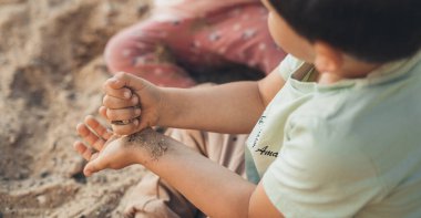 İki kardeş evlerinin bahçesinde kum ve taşlarla oynuyorlar. Aile aktivitesi konsepti. Yaz tatili kavramı.