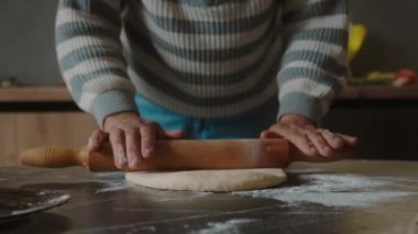 Mutfak odasındaki masada hamuru oklavayla saran tanınmamış kadınlar. Yemek hazırlama..