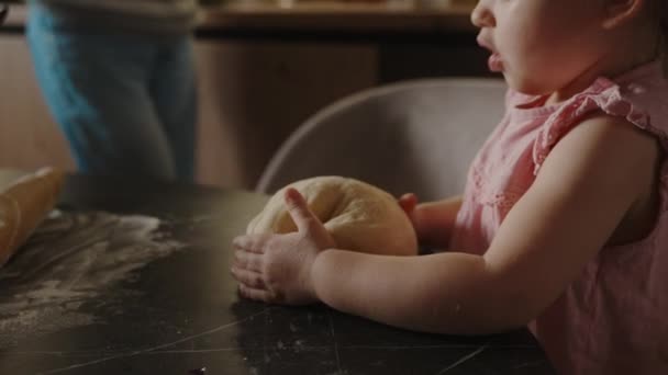 Baby Girl Sitting Kitchen Table Holding Dough Her Hand Trying — Stock Video