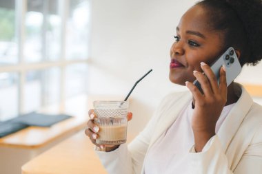 Buzlu kahveyle milenyum kadını işten sonra bir kafede oturup uluslararası telefon görüşmesi yapıyor. Çevrimiçi iletişim.