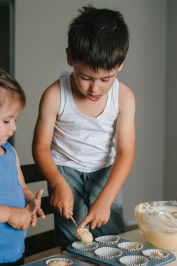 Kafkasyalı çocuk mutfaktaki silikon kalıplara hamur döküyor. Şekerleme pişirme kavramı. Lezzetli yemek. Yemek hazırlama. Tatlı yemek..