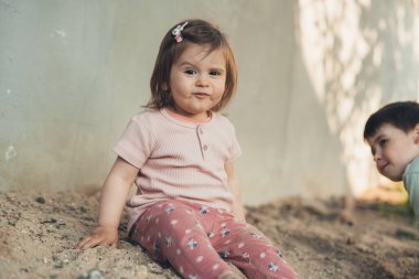 Arka bahçede çocuklar için oynarken kameraya bakan komik küçük kız. Açık hava çocuk parkı, aile eğlence zamanı..