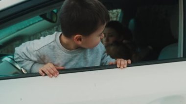 Çocuk haftasonu araba yolculuğunu beyaz renkli modern aile arabasından izlemekten zevk alıyor. Modern portre. Çocuğu oynuyorum. Aile tatili.