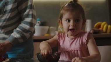 Aile yemeği, ev yapımı vişneli turta için hamur hazırlamak, bebek turtayla birlikte kasedeki kirazları yemek. Pişirme konsepti. Aile