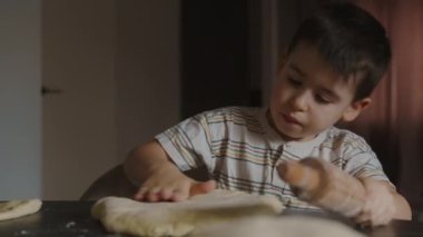 Tahta oklavayla hamur yoğurup doğum günü kurabiyesi yapan sevimli çocuk. Otantik anlar. Genç aşçı ya da şef.