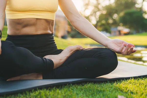 Close-up of a woman performing yoga postures at sunset sitting on yoga mat in the morning. Yoga body posture. Training workout. Fitness woman.