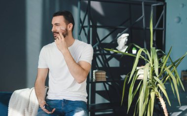 Sakallı adam evdeki güzellik masajı terapisi için yeşim taşlı yüz silindiri kullanıyor. Güzellik tedavisi. Yüz bakımı, kozmetoloji. Yüz derisi..