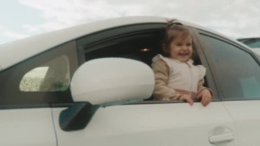 Minibüsün camından sarkan, gülümseyen ve birlikte oynayan iki tatlı kardeş. Yaz tatili. Çocuk konseptiyle araba yolculuğu.