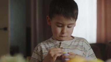 Paskalya tatili için yumurtaları evin mutfağına boyayan çocuk. Çocuk eğleniyor ve ziyafeti kutluyor. Şenlik dekorasyonu. Paskalya eğlencesi.