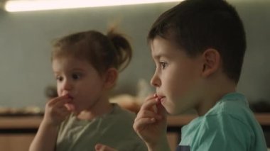 Ağabeyi ve kız kardeşi evde mutfak masasında otururken dizüstü bilgisayar ya da defter kullanıyorlardı. Çocuklu aile. Ev konseptinde hafta sonu aktiviteleri.