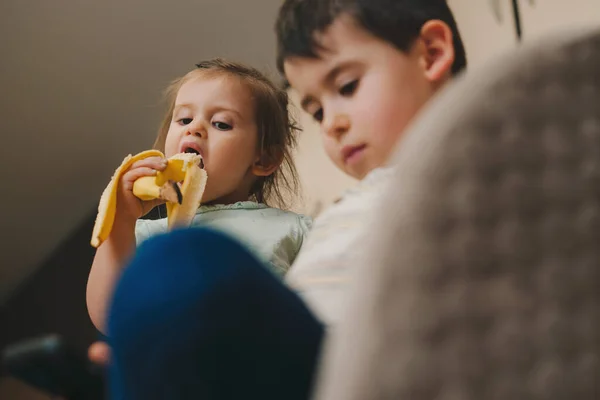 Uma Criança Sentada Numa Cadeira Comer Uma Banana Madura Olhar — Fotografia de Stock