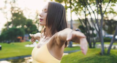 Parkta yoga egzersizi yapan, meditasyon pozu veren, sağlık hizmeti veren bir kadının yakın çekim görüntüsü. Yoga ve meditasyon konsepti