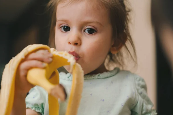Uma Menina Saudável Comer Banana Olhar Para Câmara Sala Das — Fotografia de Stock