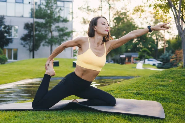 Spor giyimli beyaz kadın şehir parkında bacak esnetiyor. Sağlıklı yaşam tarzı, spor. Pozitif kişi. Fitness kadını. Vücut pozitif. Sağlıklı