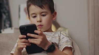 Evdeki akıllı telefondan oyun oynayan şirin bir çocuğun portresi. Akıllı telefonu tutuyorsun. Online eğitim. Çevrimiçi oyna.