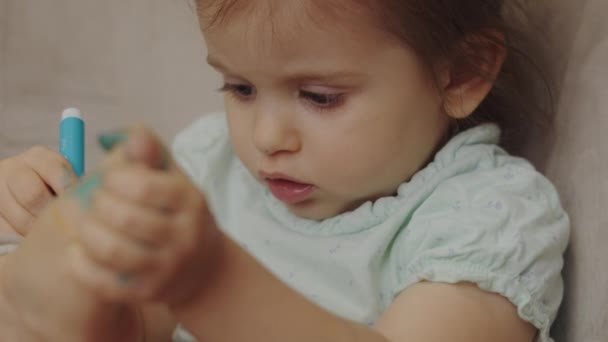 Dziewczynka Siedzi Fotelu Koncentrując Rysunek Nodze Niebieskim Markerem Dziecko Bawiące — Wideo stockowe
