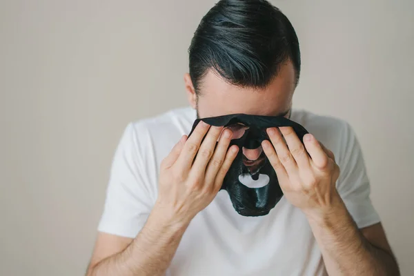 Portret Młodego Mężczyzny Zdejmującego Czarną Maskę Szarym Tle Odosobnieniu Pielęgnacyjnym — Zdjęcie stockowe
