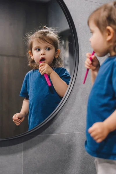 stock image Little baby girl brushing teeth with pink toothbrush, good dental hygiene practice in childhood. Dental care. Healthy concept.