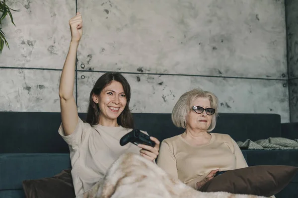 两个高加索女人坐在沙发上 靠在沙发上 用无线控制杆玩电子游戏 高加索家庭的娱乐 — 图库照片