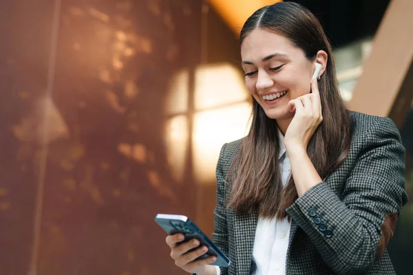 stock image Portrait of a happy young employee business woman in classic formal jacket sitting outside the office building. Mobile phone communication. Beautiful woman face