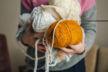 Ellerinde renkli yün iplikler tutan bir kadın. Örgü örmenin yaratıcı bir konsepti. Örgü, dikiş malzemeleri..