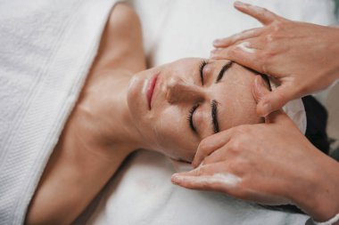 Spa salonundaki kadın yüz masajı yaptırıyor. Kız yüz tedavisi. Cilt bakımı. Vücut bakımı.