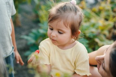 Parkta vakit geçirirken anonim bir anneyle oynayan sıradan giysili sevimli küçük kızın yüksek açısı.