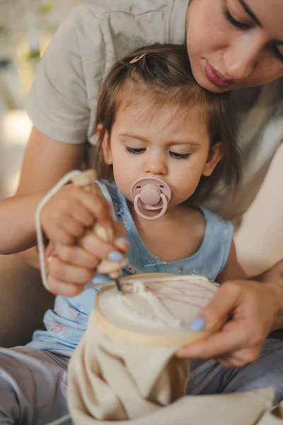 stock image High angle of cute little girl in casual clothes sitting at table and playing with crop mother