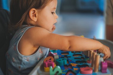 Evde renkli oyuncaklarla oynayan sevimli küçük kızın yan görünüşü