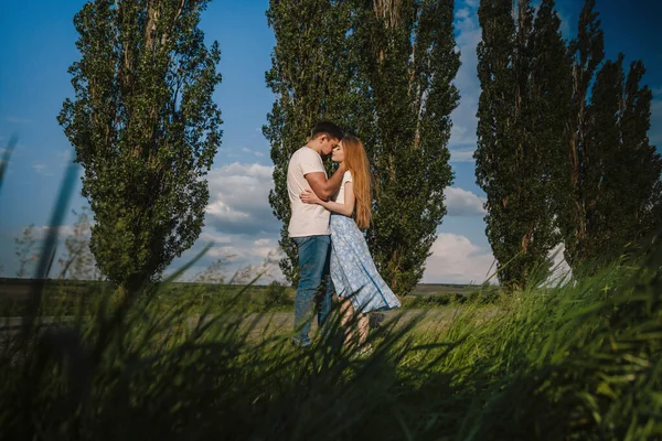 夜に草の牧草地に立っている間 愛の抱擁とお互いを見ての愛のカップルのサイドビュー — ストック写真