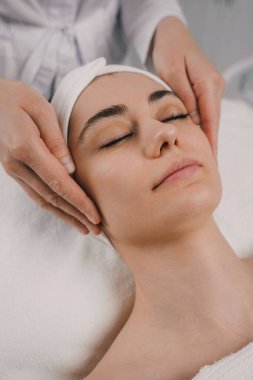 Ekin masözü müşteriye yüz masajı yapıyor.