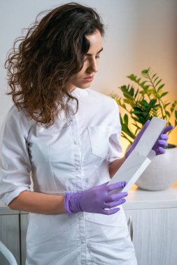 Estetikçi dolabındaki beyaz bir kutuya bakıyor. .