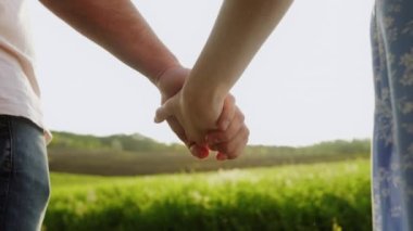 Gün batımında bir tarlada el ele tutuşan bir çiftin detaylı planı. Yüksek kalite 4k görüntü