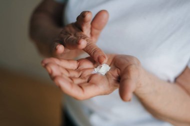 Anonim bir kadının arka planda nemlendirici krem sürerken yüksek açılı görüntüsü.