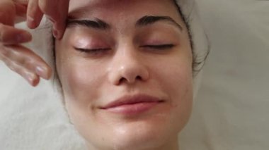 Close up view of a satisfied woman face getting a spa treatment with cream. Enjoying skincare procedure.
