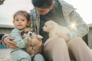 Sevimli çift kızı ve annesi evcil hayvanlarıyla arka bahçede oturuyor. Bahçedeki aile. Anne ve kızı. Küçük köpeği olan insanlar..