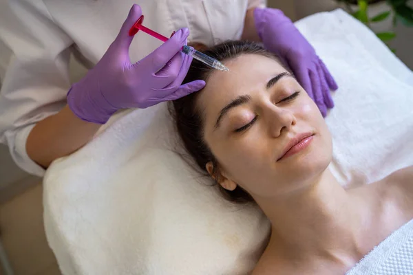 俯瞰一位女性面部注射年轻化药物 在美容院进行抗衰老非外科整容手术 戴手套的美容师专业手 — 图库照片