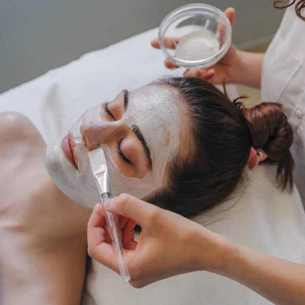 女性专业美容师用手为面部皮肤护理的病人戴口罩 女性客户闭眼放松 享受温泉 — 图库照片